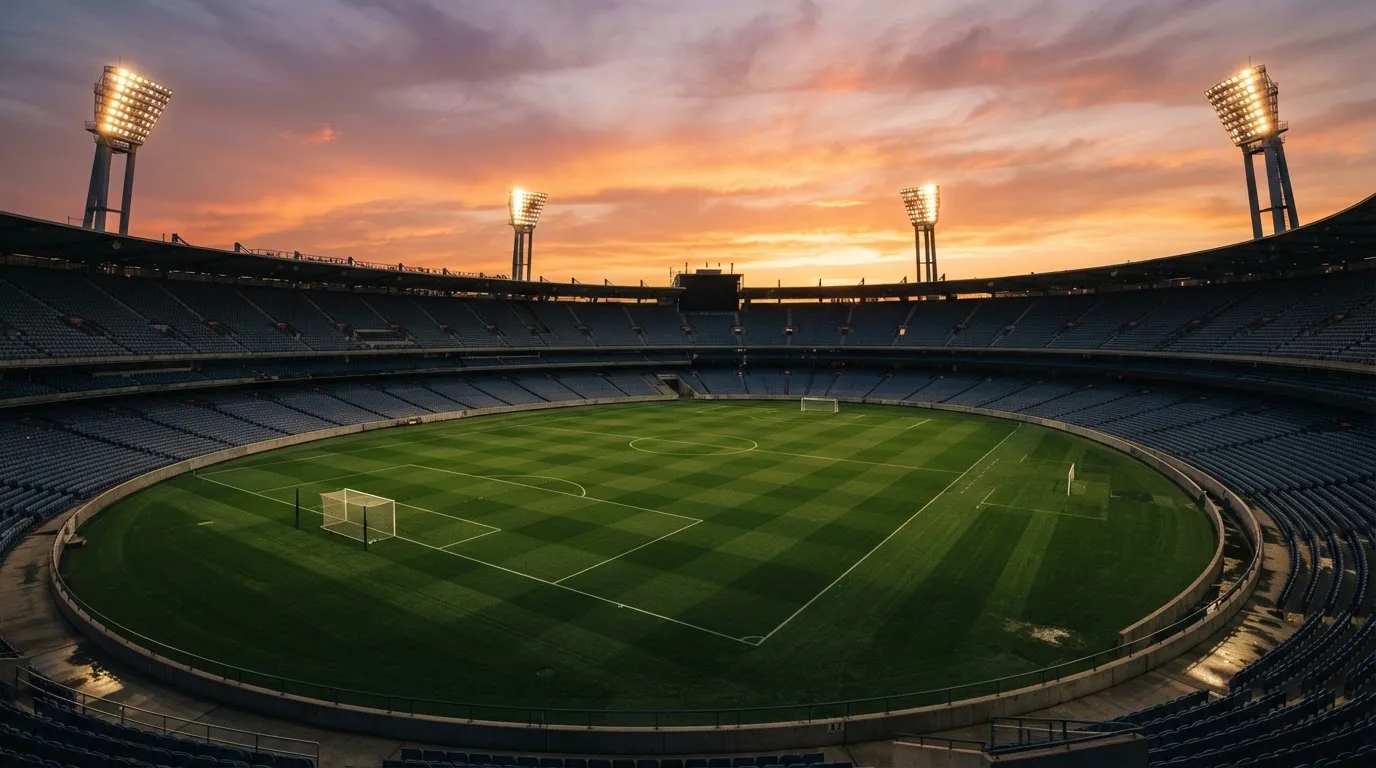 Un estadio de fútbol vacío con torres de iluminación al atardecer