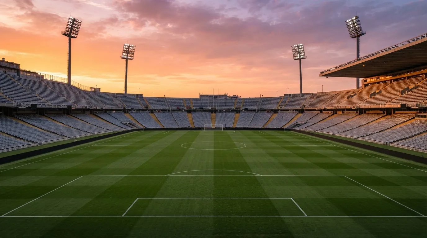 Un estadio de fútbol vacío con torres de iluminación al atardecer