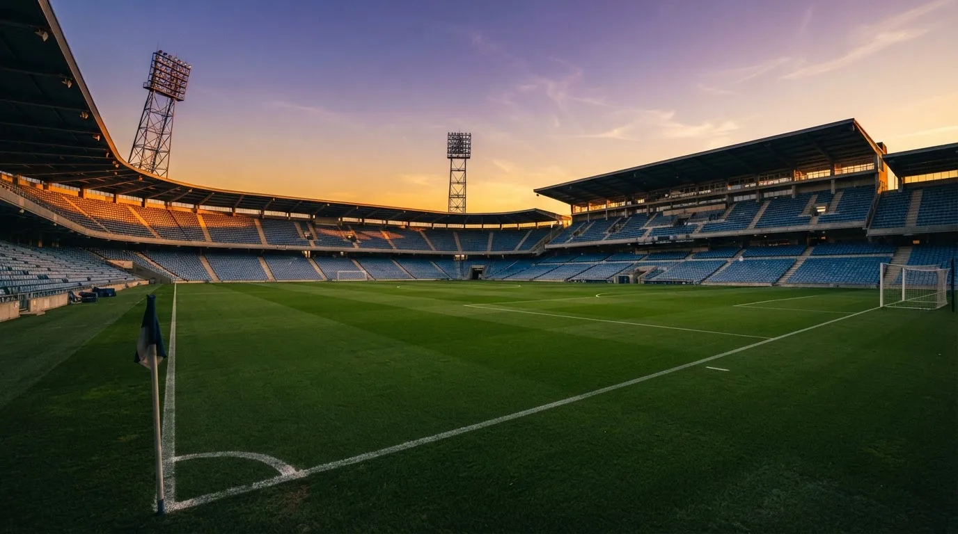 Un estadio de fútbol vacío con torres de iluminación al atardecer