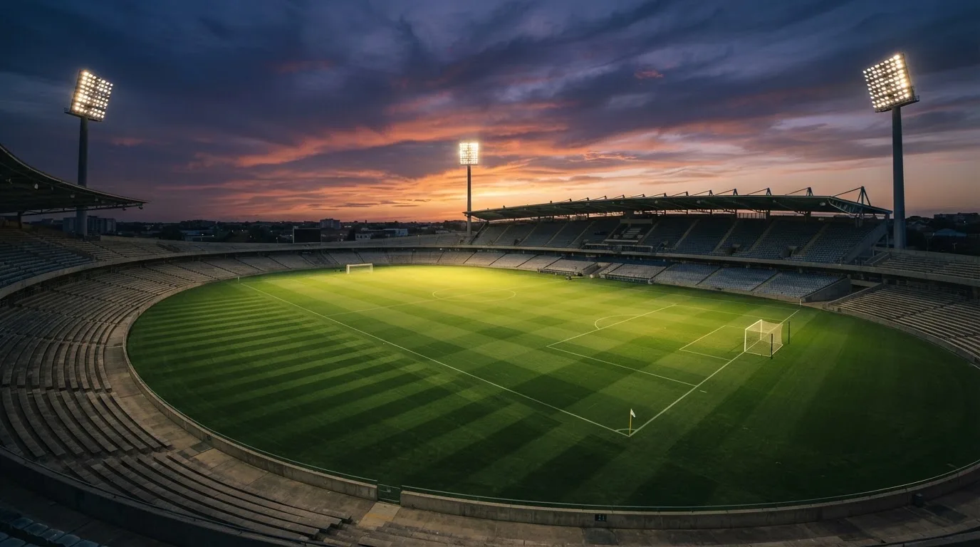 Un estadio de fútbol vacío con torres de iluminación al atardecer