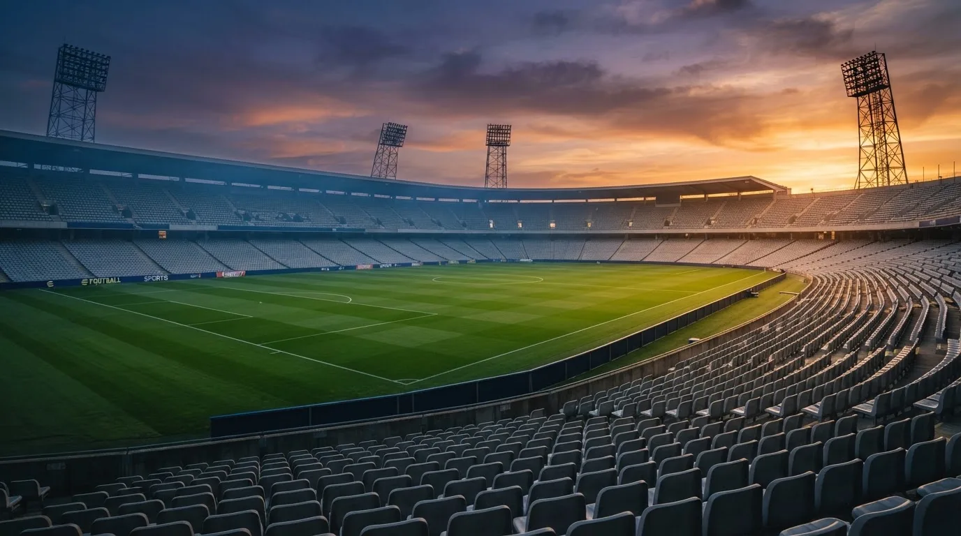Un estadio de fútbol vacío con torres de iluminación al atardecer