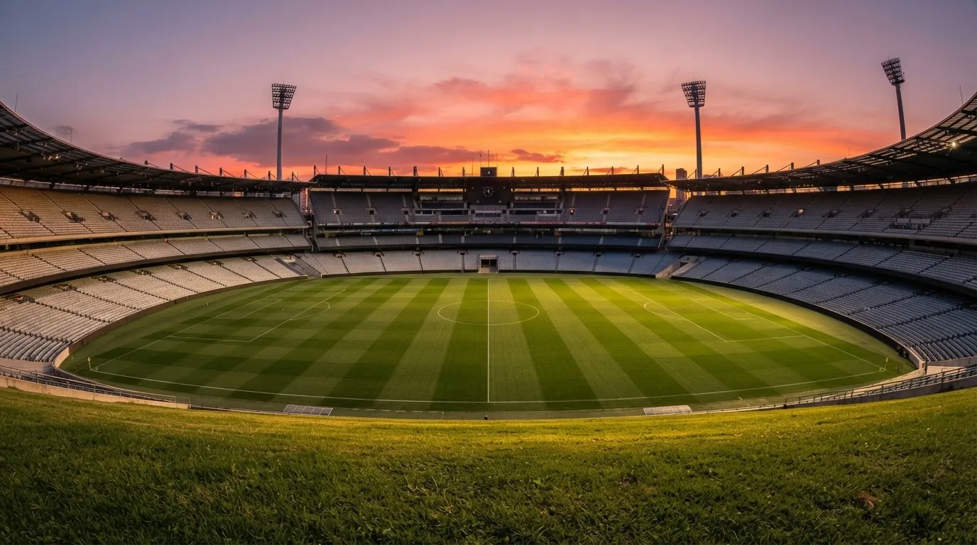 Un estadio de fútbol vacío con torres de iluminación al atardecer