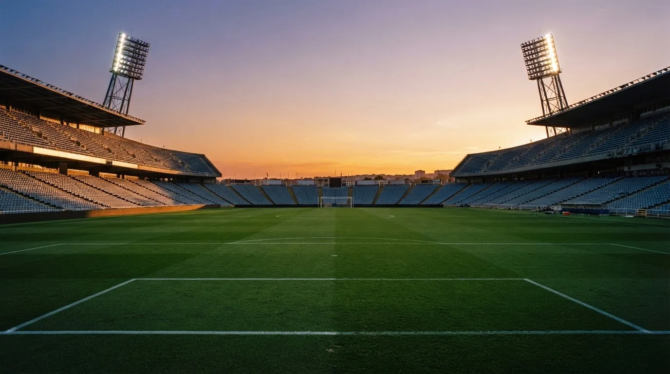 Un estadio de fútbol vacío con torres de iluminación al atardecer
