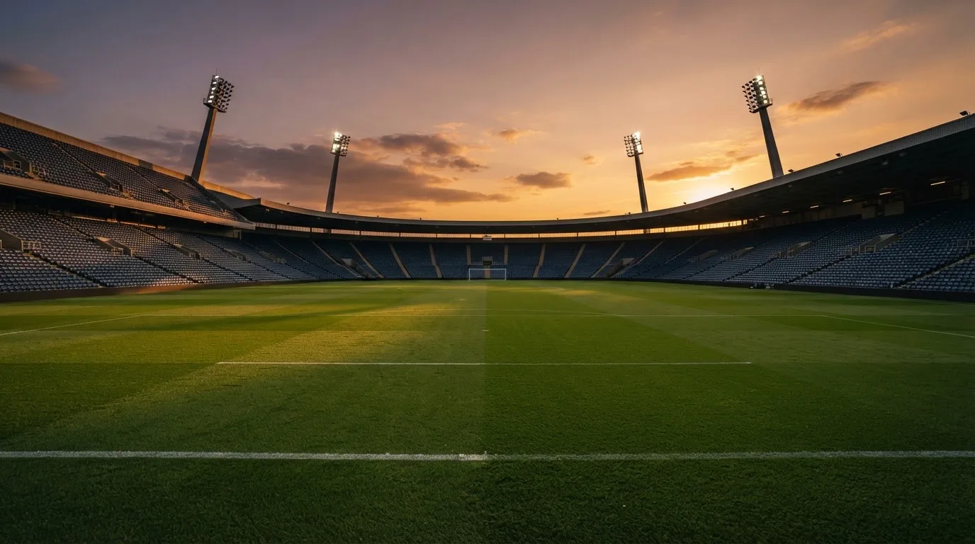 Un estadio de fútbol vacío con torres de iluminación al atardecer