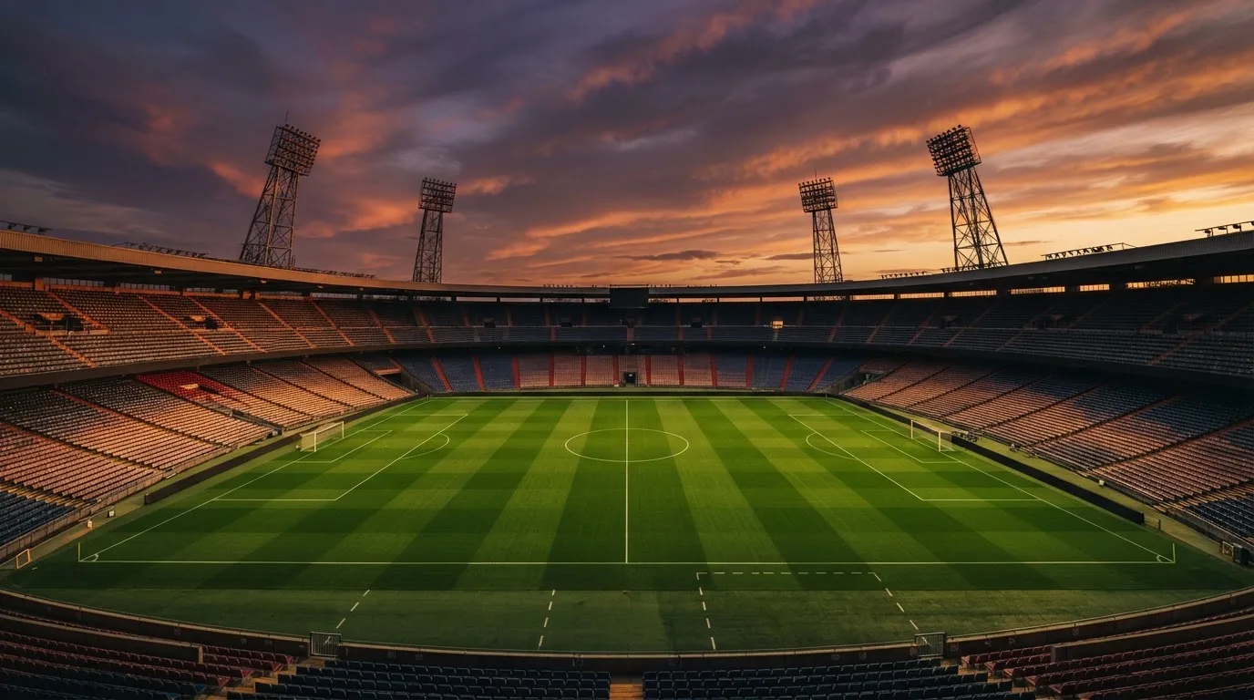 Un estadio de fútbol vacío con torres de iluminación al atardecer