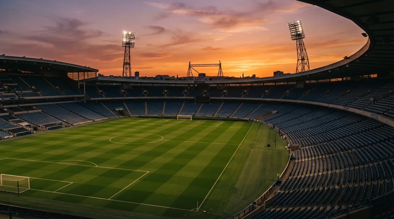 Un estadio de fútbol vacío con torres de iluminación al atardecer