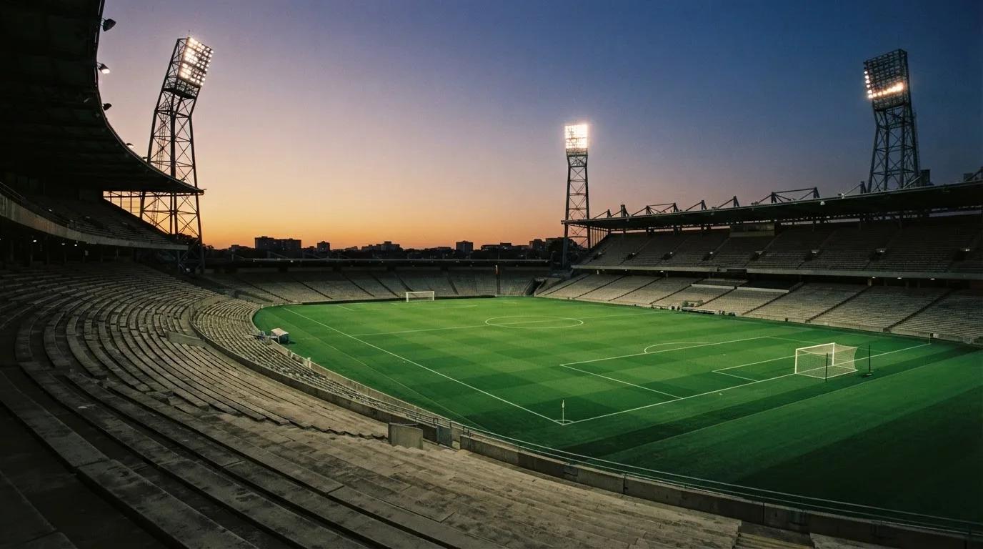 Un estadio de fútbol vacío con torres de iluminación al atardecer