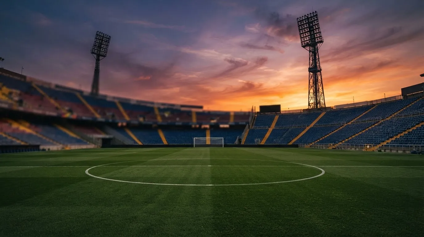 Un estadio de fútbol vacío con torres de iluminación al atardecer