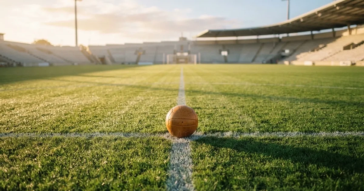 Un balón en el punto central de un campo de césped a la luz de la mañana