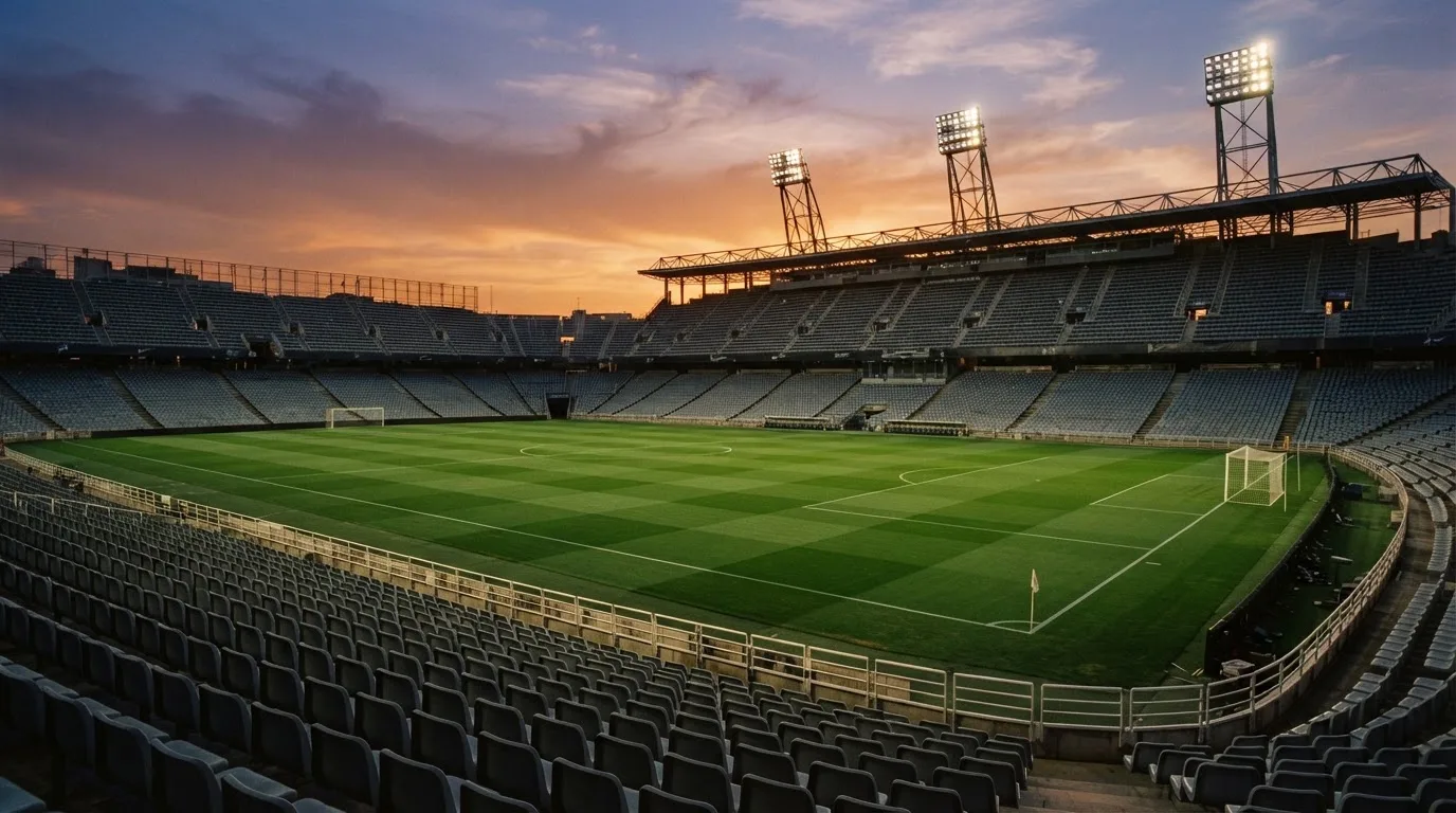 Un estadio de fútbol vacío con torres de iluminación al atardecer