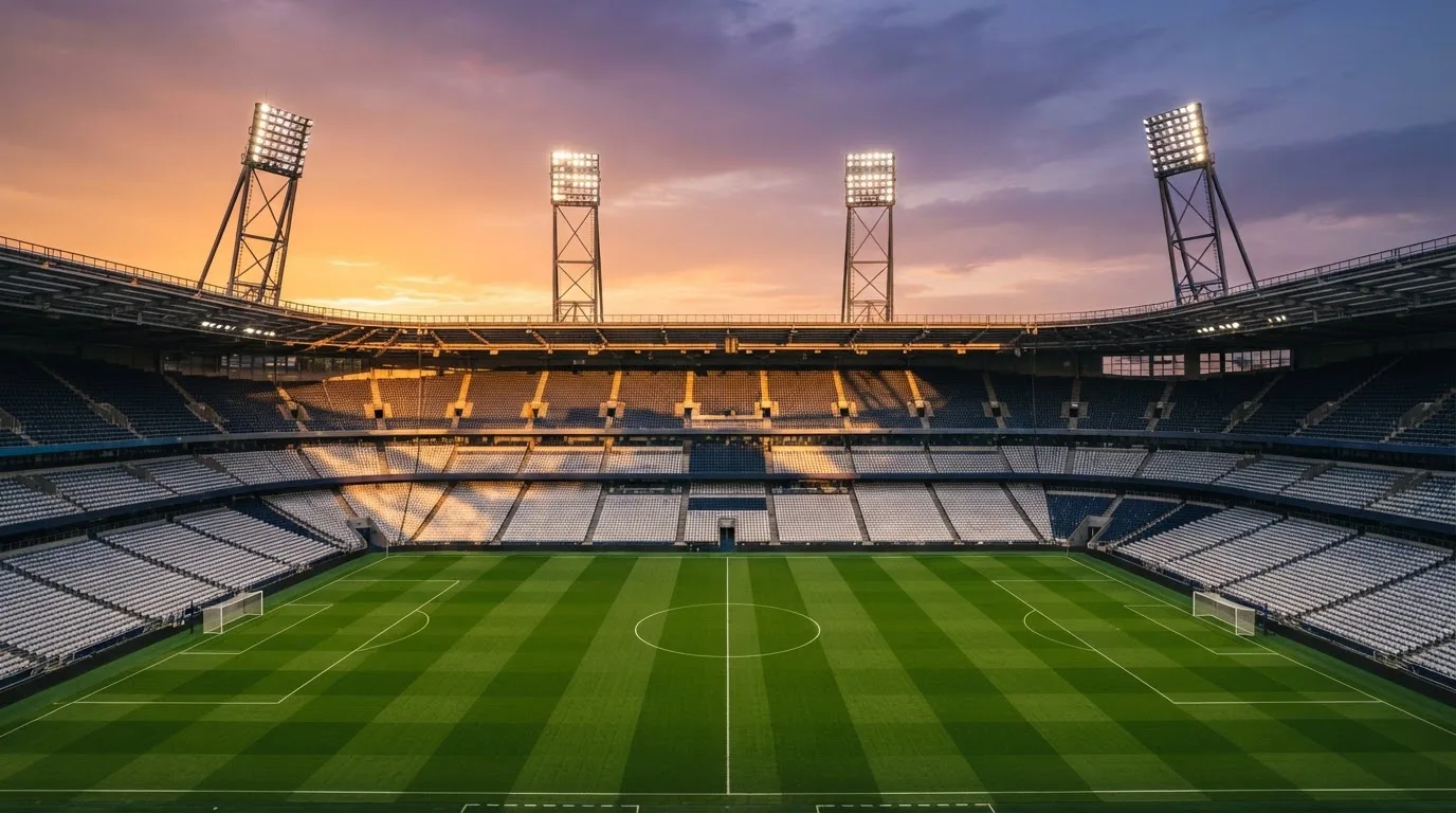 Un estadio de fútbol vacío con torres de iluminación al atardecer