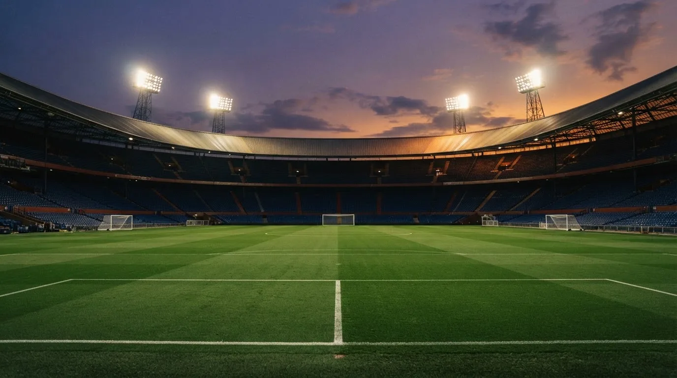 Un estadio de fútbol vacío con torres de iluminación al atardecer