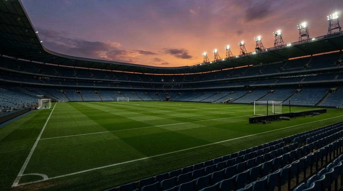Un estadio de fútbol vacío con torres de iluminación al atardecer