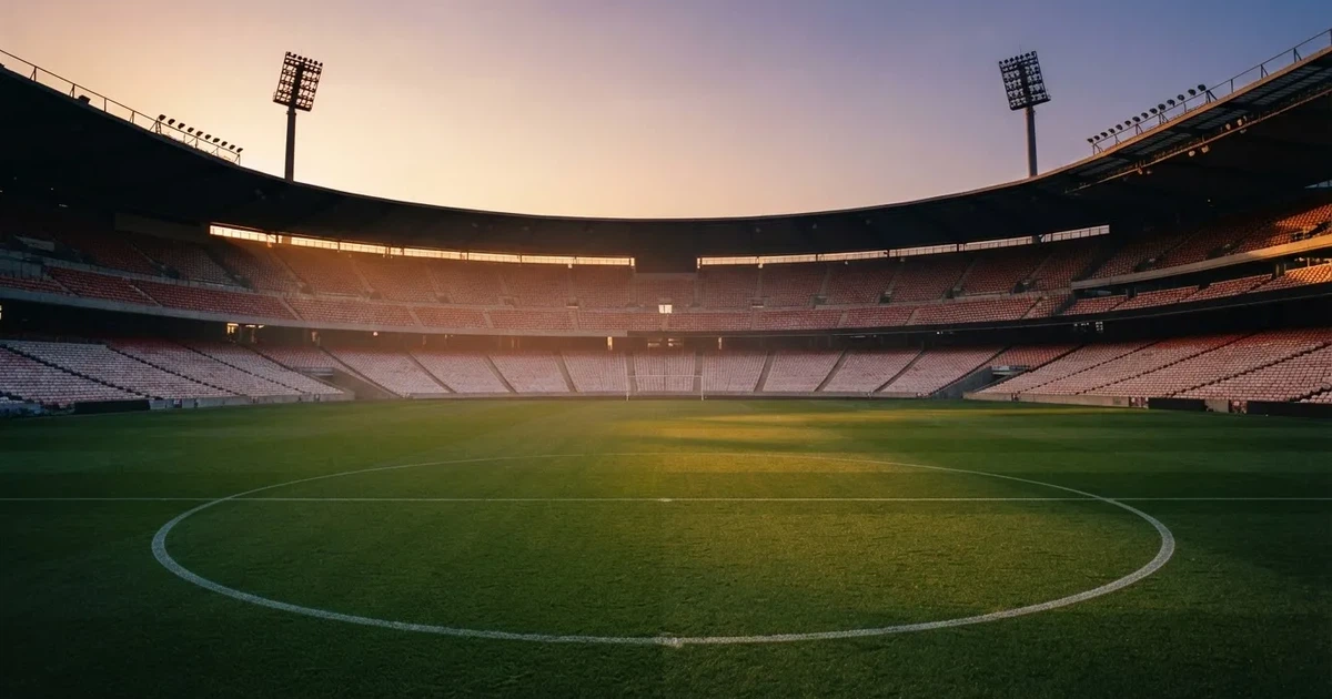 Un estadio de fútbol vacío con torres de iluminación al atardecer
